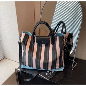 Detail of striped canvas tote with pink and grey pattern, leather handles and silver clasp