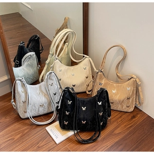 Detail of multi-color pleated shoulder bags featuring metallic butterfly charms on surface