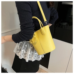Detail view of yellow lychee pattern leather bucket bag with cute elephant charm