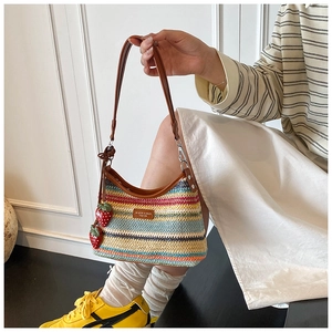 Détail d'un sac à bandoulière en paille tissée colorée avec pendentifs fraises décoratifs
