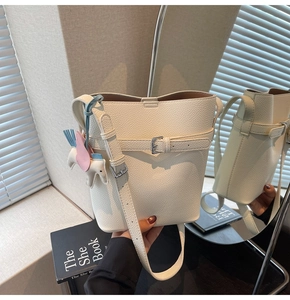 Detail of white lychee leather bucket bag with silver buckle and pastel horse charm