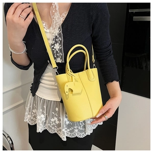 Close-up of a yellow lychee-textured bucket bag with a cute elephant charm