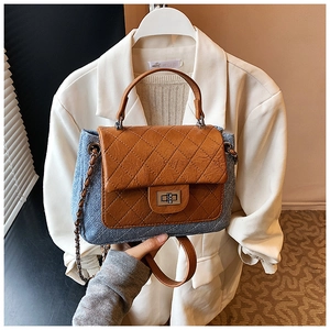 Detail view of denim and brown leather quilted handbag with metal chain strap