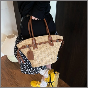 Detail of hand-woven straw basket bag with dark brown leather handles and metal buckles