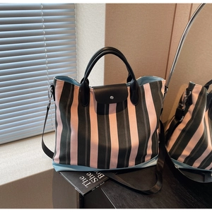 Detail view of pink and green striped tote bag with leather flap and detachable strap
