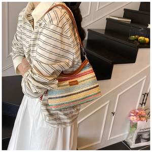 Détail du sac tissé arc-en-ciel avec bandoulière en cuir marron et plaque de marque