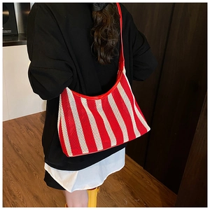 Vue détaillée du dos d'un sac hobo en maille rayé rouge et blanc porté à l'épaule