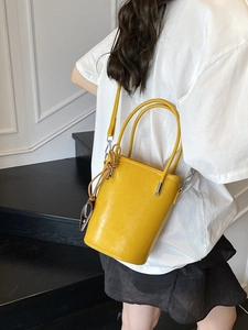 Chic yellow glossy leather bucket bag with top handle and adjustable crossbody strap