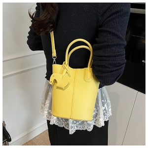 Detail showing bright yellow litchi grain leather bucket bag with cute elephant charm