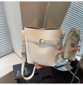 Detail of white lychee pattern bucket bag with decorative buckle and horse charm