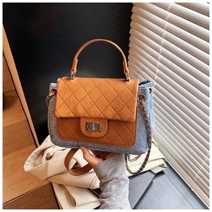 Detail of blue denim and brown leather handbag with diamond quilting and silver lock
