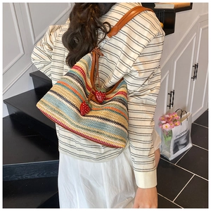 Sac bandoulière tissé à rayures arc-en-ciel avec breloques fraises sur un mannequin