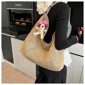 Detail of large woven straw tote bag with cute plush puppy charm in a modern kitchen setting
