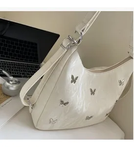 Detail of white glossy wrinkled shoulder bag with silver metal butterfly accents
