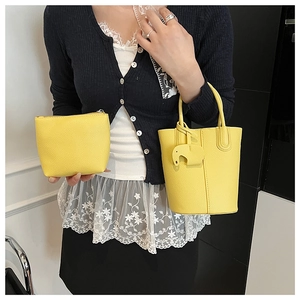 Close-up of bright yellow lychee grain leather bucket bag set with elephant charm detail