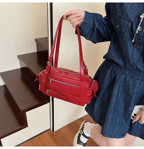 Close-up of vibrant red glossy leather shoulder bag with silver metallic zippers