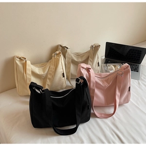 Detailed display of four minimalist canvas hobo bags in neutral tones on white bedding