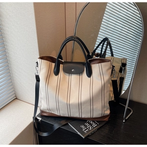 Detail of canvas tote bag with brown stripes, leather trim, and adjustable shoulder strap