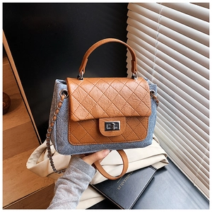 Detail of blue denim quilted bag with brown leather flap and silver twist lock