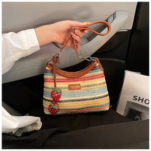 Détail d'un sac cabas tissé coloré avec breloques fraises et poignées en cuir brun