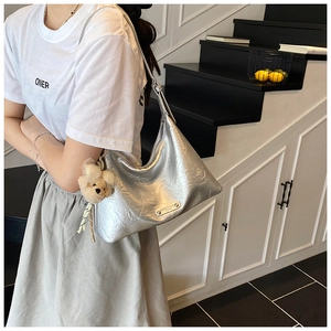 Gros plan du sac hobo plissé argenté avec pendentif ours sur l'épaule du mannequin