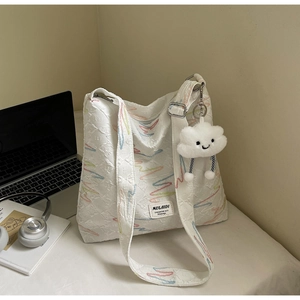 Detail view of white canvas tote bag with wave embroidery and a cute cloud charm