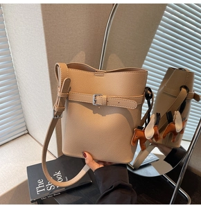 Detail of beige lychee pattern bucket bag with adjustable strap and horse charm