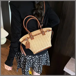 Detail of hand-woven straw tote with brown leather handles and a side leather tag