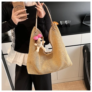 Detail of straw woven tote bag featuring a cute dog plush charm and leather handles