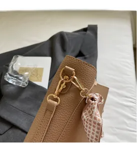 Detail of light brown lychee grain leather bucket bag with gold hardware and silk scarf