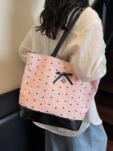 Borsa tote trapuntata rosa con fiocchi neri e ciondolo a cuore indossata da una modella