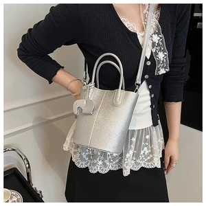 Silver lychee leather bucket bag with top handles and adjustable strap on model