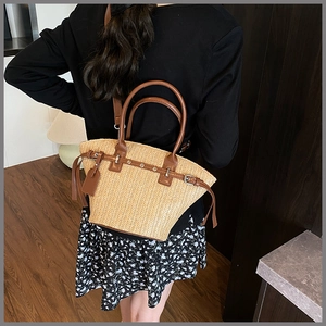 Detail of woven straw beach bag featuring brown leather handles and rivet accents