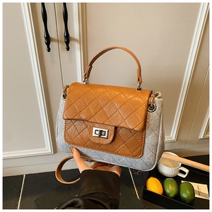 Close-up of quilted grey fabric and brown leather shoulder bag with silver twist lock
