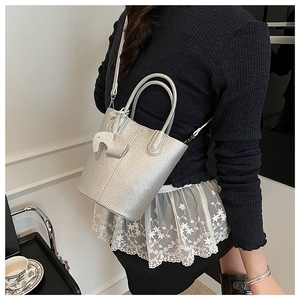 Silver bucket bag with litchi texture and elephant charm detail shown on a model