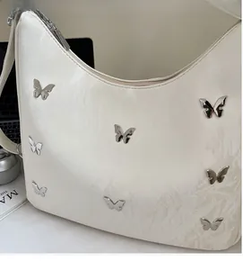 Detailed view of silver butterfly metal accents on the beige wrinkled leather hobo bag