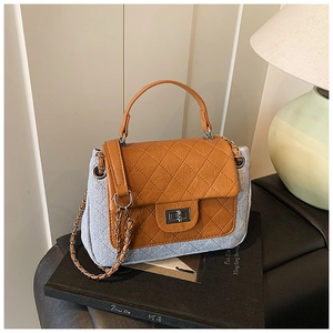Detail of grey quilted canvas handbag with brown leather flap and silver twist-lock closure