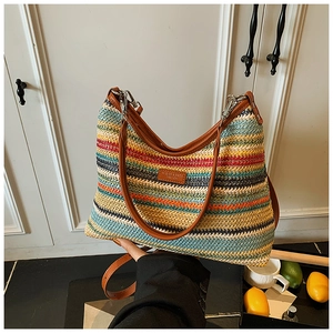 Détail d'un sac tissé rayé arc-en-ciel avec des poignées en cuir marron et une bandoulière