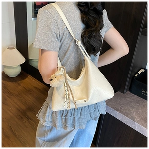 Détail du sac hobo en cuir plissé beige avec charm ours en peluche et corde tressée