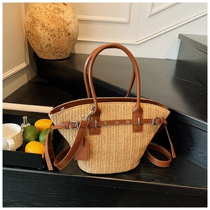 Detail of woven straw tote bag with brown leather handles and decorative silver buckle