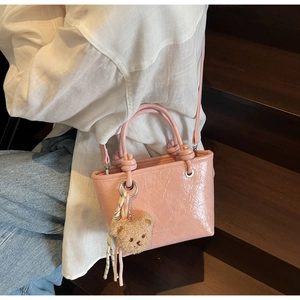 Pink pleated mini bucket bag with teddy bear charm and silk scarf on white shirt