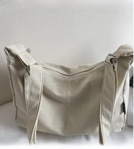 Detail of off-white large capacity crossbody bag showing silver zipper and adjustable strap