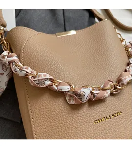 Detail of lychee pattern leather bucket bag with silk scarf wrapped chain strap and logo