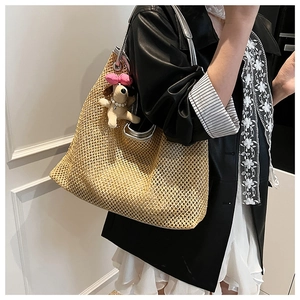 Detail of straw woven tote bag featuring silver circular metal handle and cute puppy charm