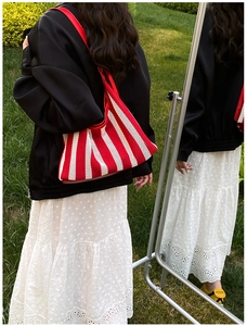 Sac fourre-tout en maille rayée rouge et blanc reflété dans un miroir de jardin