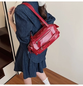 Detail of dark red glossy leather shoulder bag with side buckle and metal hardware
