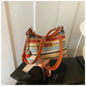 Détail du sac en paille tressée arc-en-ciel avec bandoulière en cuir et pendentif fraise