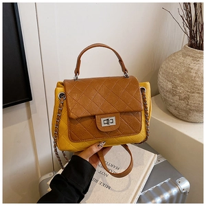 Close-up of contrast color handbag featuring diamond stitching and silver turn-lock closure