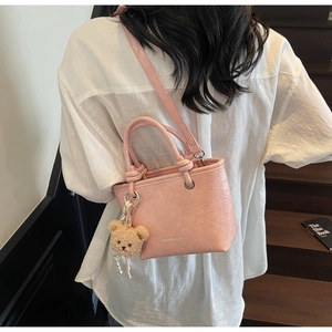 Detail of pink crinkled leather mini tote with plush bear charm and crossbody strap
