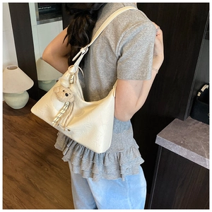 Détail du sac hobo plissé crème avec un joli pendentif peluche ours brun sur la bandoulière